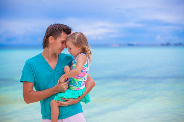 Padre felice e la sua adorabile piccola figlia in spiaggia di sabbia bianca