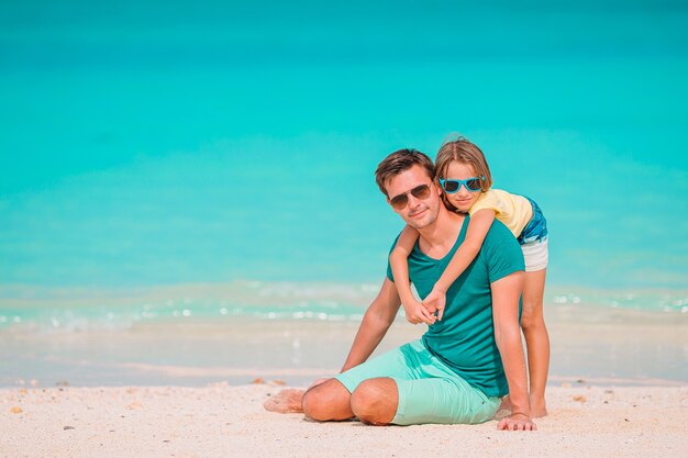 Padre felice e la sua piccola figlia adorabile alla spiaggia di sabbia bianca divertendosi