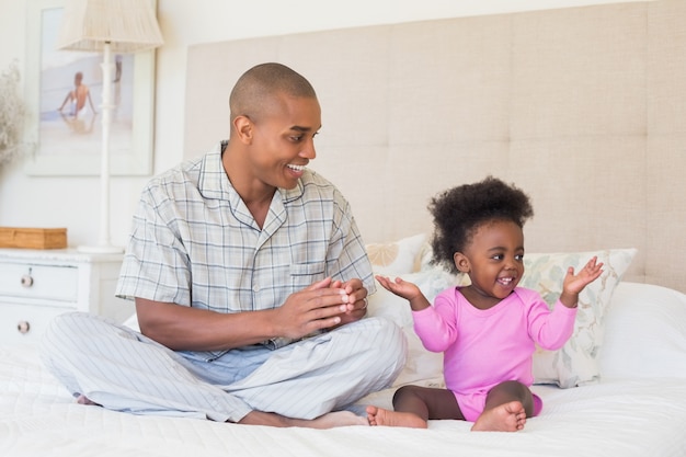 Padre felice e neonata che si siedono insieme sul letto