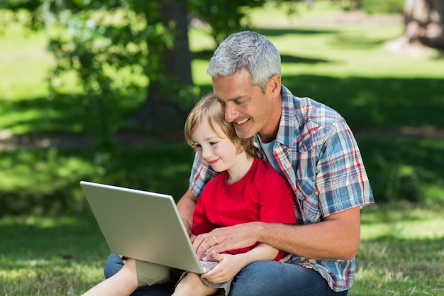 Padre felice usando il portatile con suo figlio