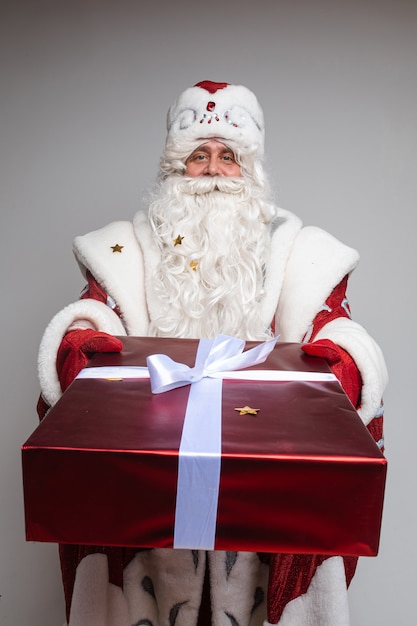 Padre gelo fa un grande regalo alla fotocamera, immagine isolata sul muro bianco