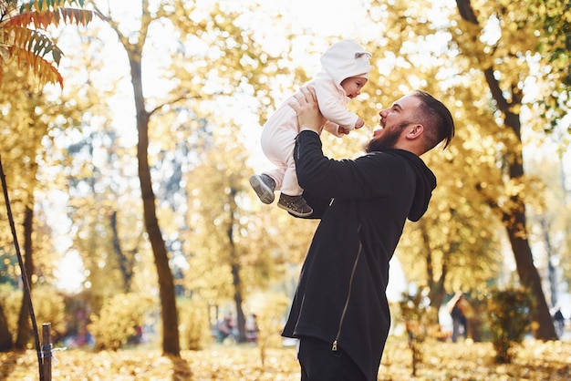 Padre in abiti casual con suo figlio è nel bellissimo parco autunnale.