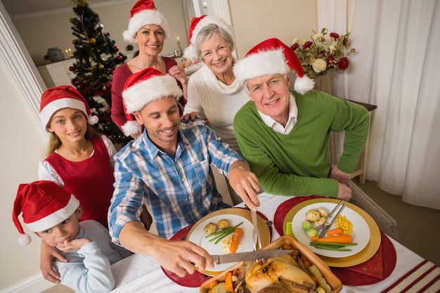 Padre in cappello della santa che intaglia pollo durante la cena di Natale