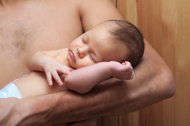 Padre in possesso di un neonato che dorme nelle sue mani