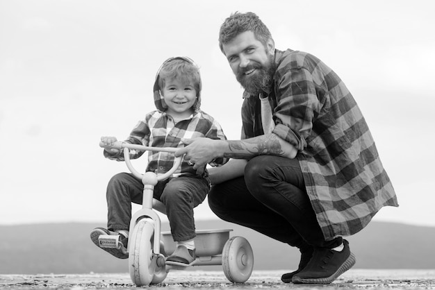 Padre insegna a suo figlio ad andare in bicicletta il ragazzino impara ad andare in bicicletta con il suo papà papà t