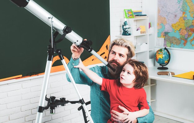 Padre insegnamento figlio bambini educazione scientifica concetto astronomia telescopio bambini scuola contro cha verde