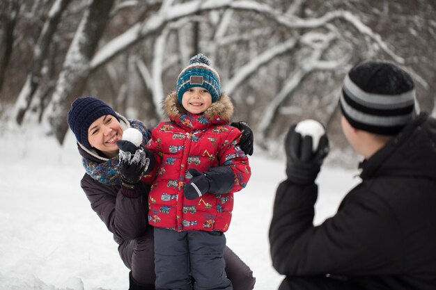 Padre, madre e figlio che giocano a palle di neve in inverno Park