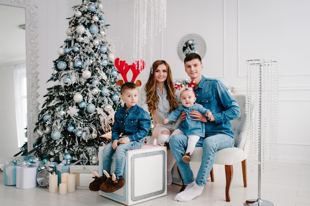 Padre, madre tiene figlio e figlia vicino all'albero di Natale