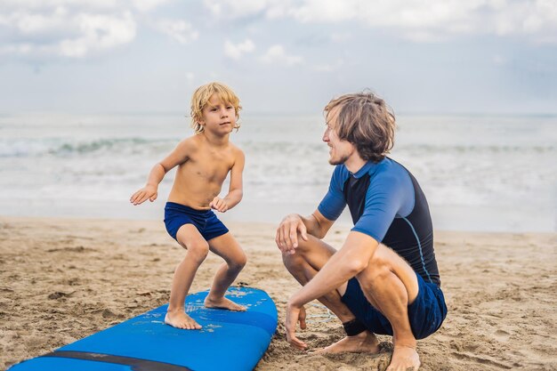 Padre o istruttore insegna a suo figlio di 4 anni come fare surf in mare in vacanza o in vacanza. Viaggi e sport con il concetto di bambini. Lezione di surf per bambini