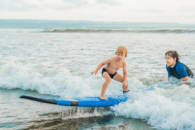 Padre o istruttore insegna a suo figlio di 4 anni come fare surf in mare in vacanza o in vacanza. Viaggi e sport con il concetto di bambini. Lezione di surf per bambini