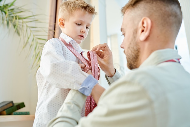 Padre premuroso che veste suo figlio