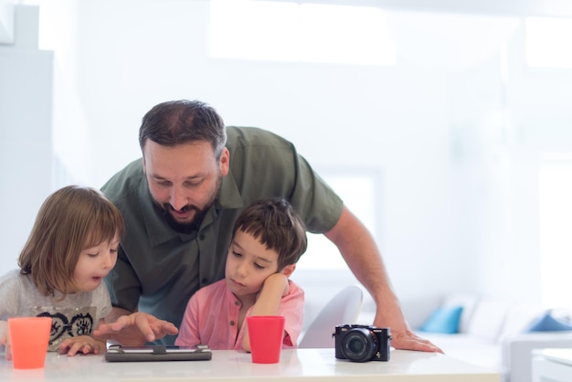 padre single a casa con due bambini che giocano e danno lezioni di educazione su tablet a casa moderna
