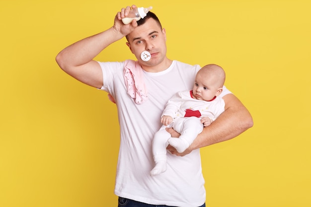 Padre stanco con il manichino del bambino in bocca, tenendo la mano sulla fronte