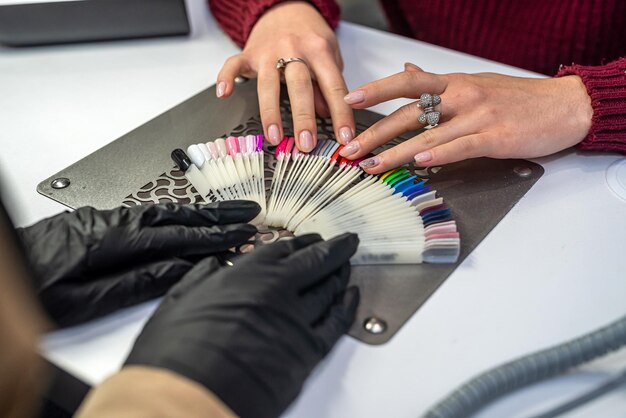 Padroneggia con un cliente che sceglie il colore dello smalto per unghie nel salone di bellezza