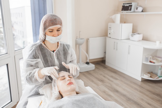 Padroneggia una procedura cosmetica per il suo cliente. trattamento di cura della pelle. donna che fa una procedura di cura del viso.
