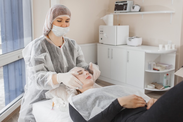 Padroneggia una procedura cosmetica per il suo cliente. trattamento di cura della pelle. donna che fa una procedura di cura del viso.