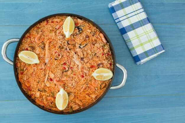 Paella di pesce su uno sfondo blu in legno