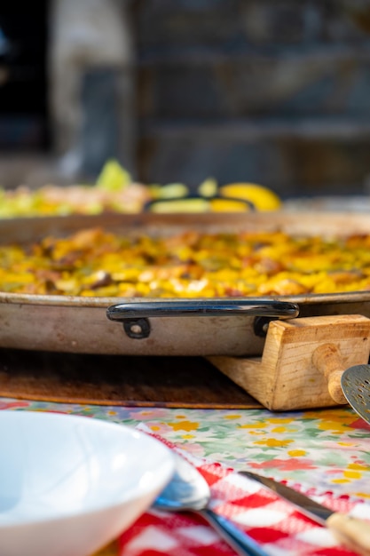 Paellera con un'autentica paella valenciana appena cucinata da servire in tavola con i piatti apparecchiati