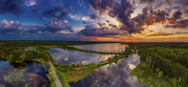 Paesaggio al tramonto estivo rurale con fiume e vista panoramica aerea sullo sfondo naturale del cielo colorato drammatico