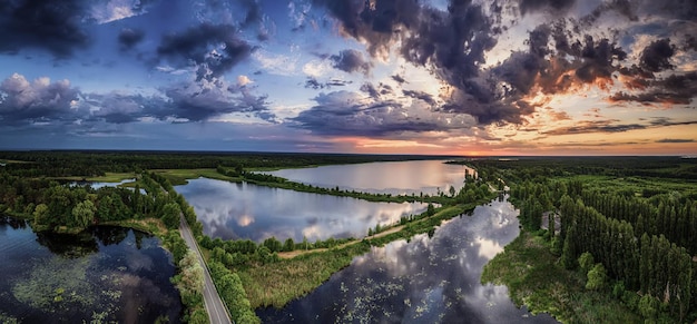 Paesaggio al tramonto estivo rurale con fiume e vista panoramica aerea sullo sfondo naturale del cielo colorato drammatico