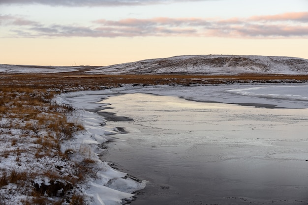 Paesaggio artico nel periodo invernale. Piccolo fiume con ghiaccio nella tundra.