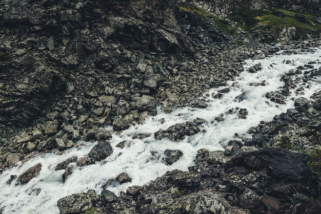 Paesaggio atmosferico con torrente di montagna tra morene in caso di pioggia.