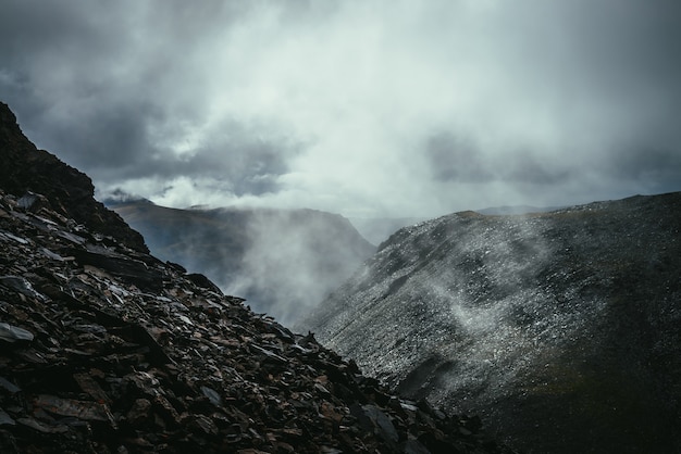 Paesaggio atmosferico scuro sull'orlo dell'abisso negli altopiani. Montagne pericolose e abissi con tempo nuvoloso. Pericolo passo di montagna e rocce taglienti tra le nuvole basse. Tempo piovoso pericoloso in montagna