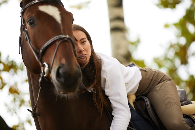 Paesaggio autunnale bella ragazza bruna con capelli lunghi in posa con un cavallo rosso nella foresta