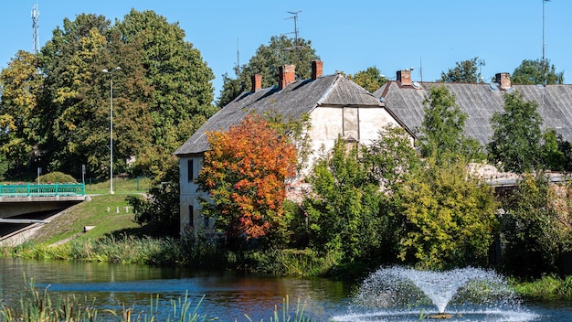 Paesaggio autunnale con edificio storico del mulino sul fiume e fontana Dobele Lettonia