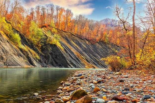 Paesaggio autunnale di un fiume che scorre tra le montagne