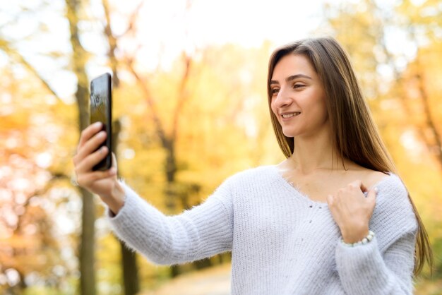 Paesaggio autunnale. Donna in abbigliamento casual in posa nel parco con foglie gialle