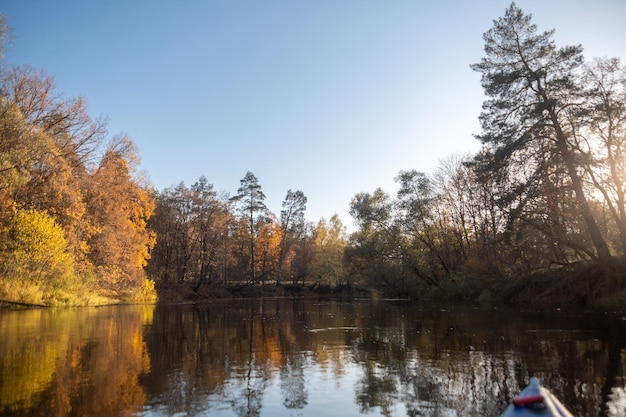 Paesaggio autunnale Il naso del kayak sullo sfondo del lago Alberi gialli sulla riva di un fiume nella foresta al tramonto Paesaggio dai colori caldi della luce del sole