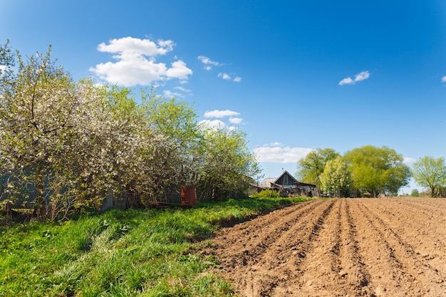 Paesaggio campo arato su uno sfondo di case rurali