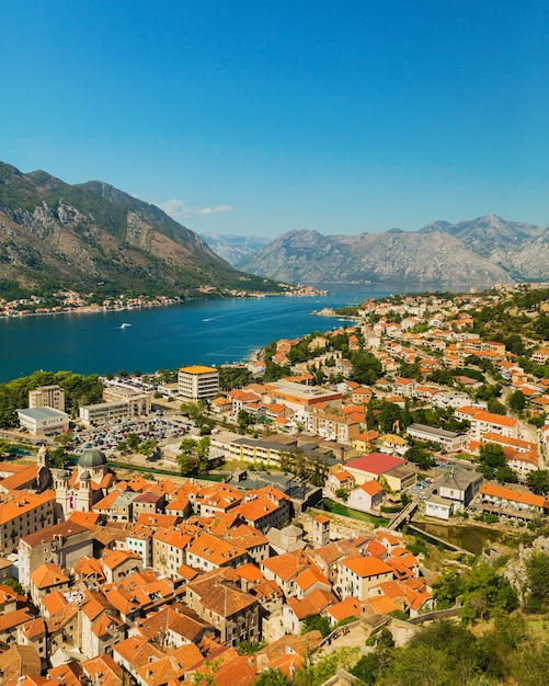 Paesaggio colorato con tetti arancioni della città vecchia, barche e yacht a Marina Bay, mare, montagne, cielo blu