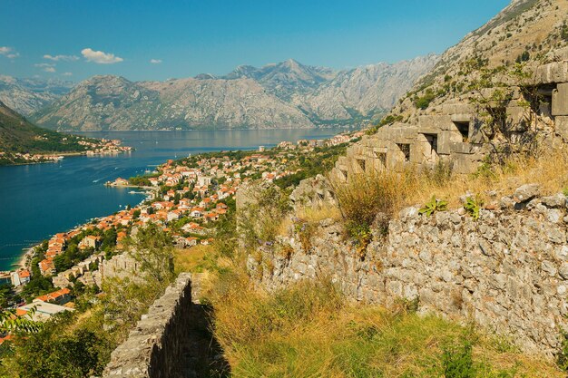 Paesaggio colorato con vecchie mura in antica cittadella, mare, montagne, cielo blu