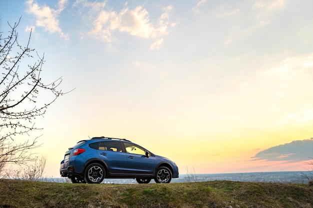 Paesaggio con fuoristrada blu al tramonto.