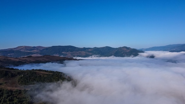 Paesaggio con montagne e nuvole che coprono la valle, vista panoramica in natura.