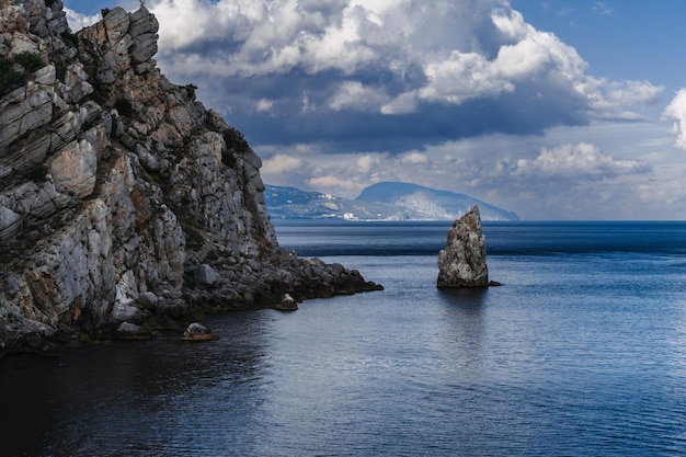 Paesaggio con montagne e rocce sul mare in una giornata estiva nuvolosa