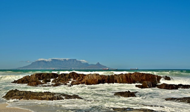 paesaggio con rocce sulla spiaggia e Table Mountain sullo sfondo