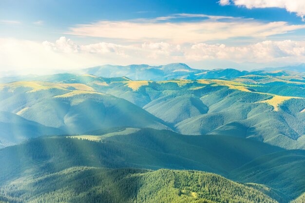 Paesaggio con tramonto, colline verdi e raggi di sole