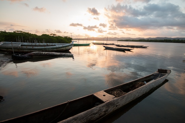Paesaggio con tramonto con canoe da pesca sul bordo del fiume.