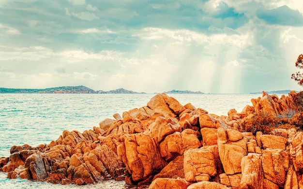 Paesaggio con tramonto romantico sulla spiaggia di Capriccioli in Costa Smeralda del Mar Mediterraneo sull'isola di Sardegna in Italia. Cielo con nuvole. Porto Cervo e provincia di Olbia. Tecnica mista.