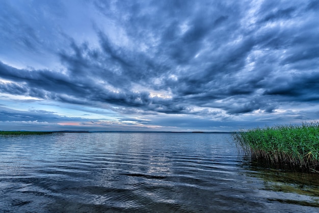 Paesaggio con un lago serale e un cielo drammatico