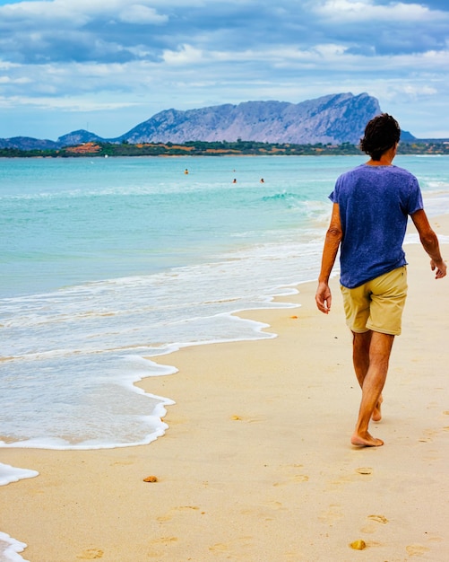 Paesaggio con uomo sulla spiaggia La Cinta e Mar Mediterraneo e Isola di Tavolara in Sardegna in Italia in estate. Vista panoramica sulla spiaggia sarda in Sardegna. provincia di Olbia. Tecnica mista.