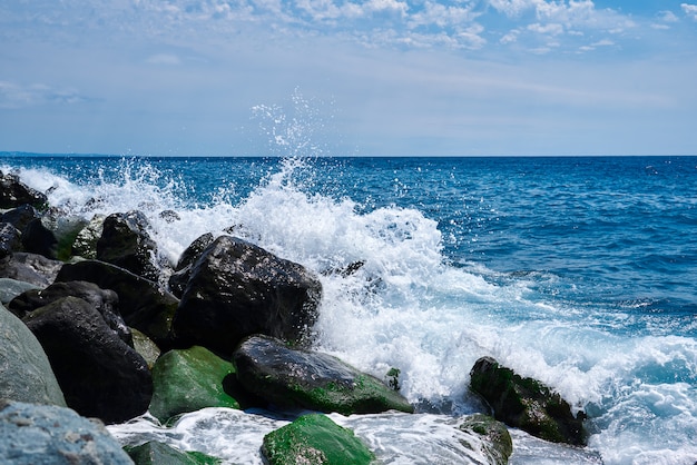 Paesaggio costiero con la calda luce della sera quando le onde si infrangono sulle rocce ricoperte di alghe