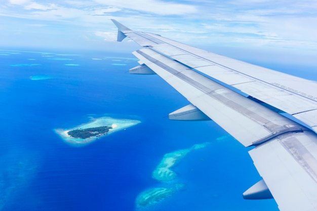 Paesaggio dalla finestra dell'aereo che vede l'ala dell'aereo nuvole bianche cielo blu Isole Maldive