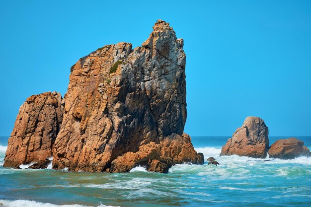 Paesaggio del mare con onde e grandi pietre e montagne