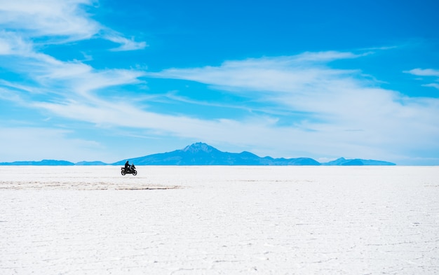 Paesaggio del sole di Salar de Uyuni in Bolivia con il motociclista che guida