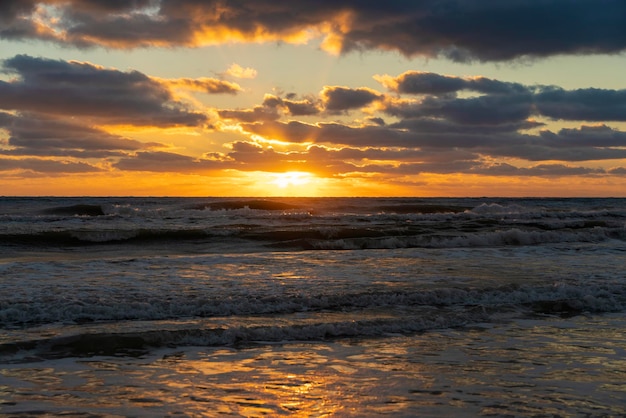 Paesaggio del tramonto dell'oceano con dolci onde d'acqua marina serale che schiacciano la spiaggia sabbiosa