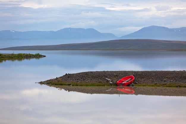 Paesaggio dell'acqua dell'Islanda con la barca rossa